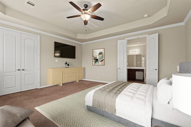 carpeted bedroom with ornamental molding, ensuite bathroom, a closet, and a tray ceiling