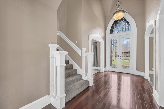 foyer entrance with a towering ceiling, dark hardwood / wood-style floors, and french doors