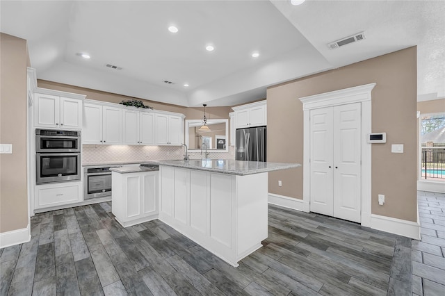 kitchen featuring white cabinetry, backsplash, light stone countertops, and appliances with stainless steel finishes