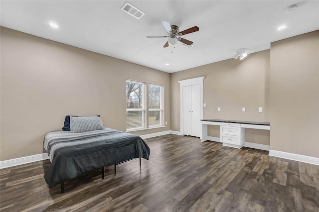 bedroom featuring built in desk, dark hardwood / wood-style floors, and ceiling fan