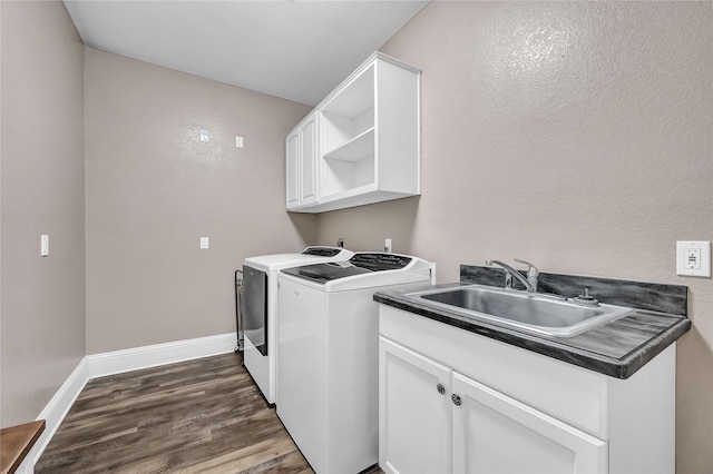 clothes washing area with washer and dryer, sink, cabinets, and dark hardwood / wood-style flooring