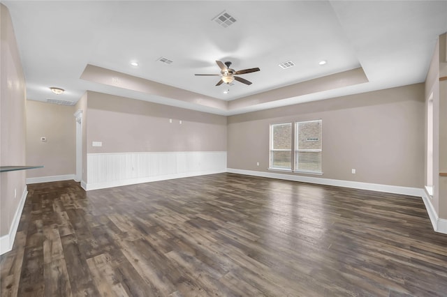 unfurnished room featuring dark wood-type flooring, a raised ceiling, and ceiling fan