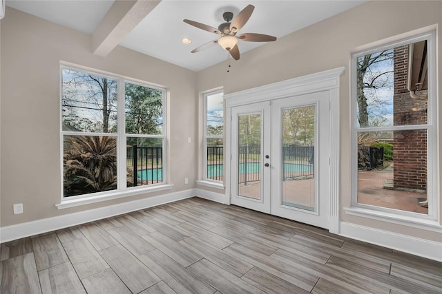 unfurnished sunroom with ceiling fan, french doors, and beamed ceiling