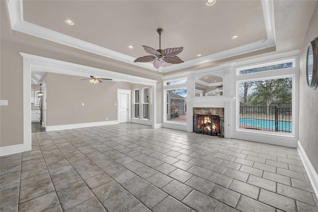 unfurnished living room with ceiling fan, ornamental molding, a raised ceiling, and tile patterned floors