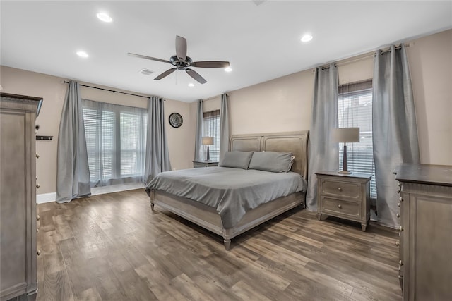 bedroom featuring ceiling fan, dark hardwood / wood-style floors, and multiple windows