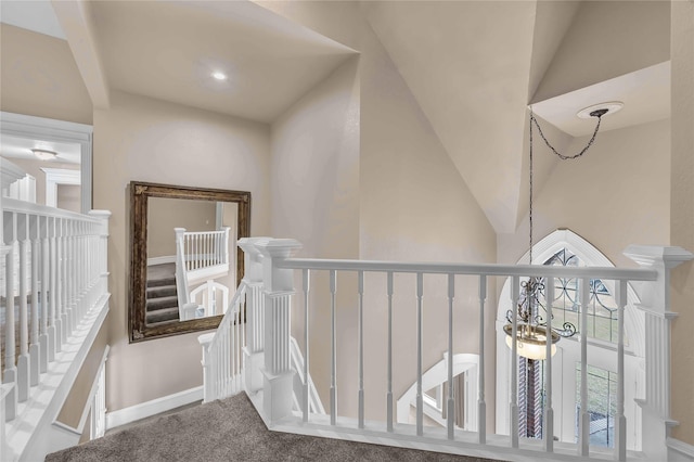 hallway featuring vaulted ceiling, carpet, and an inviting chandelier