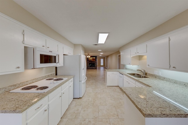 kitchen featuring sink, white cabinetry, kitchen peninsula, white appliances, and light stone countertops