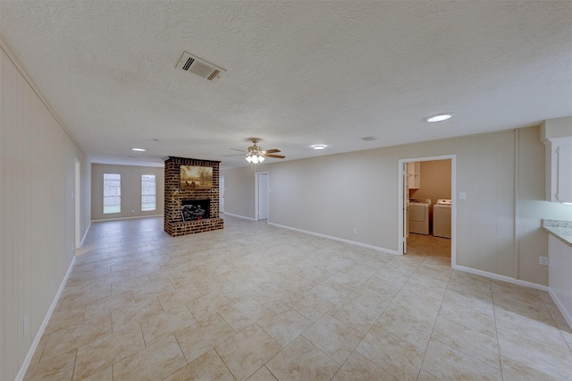 unfurnished living room with a textured ceiling, a fireplace, washing machine and dryer, and ceiling fan