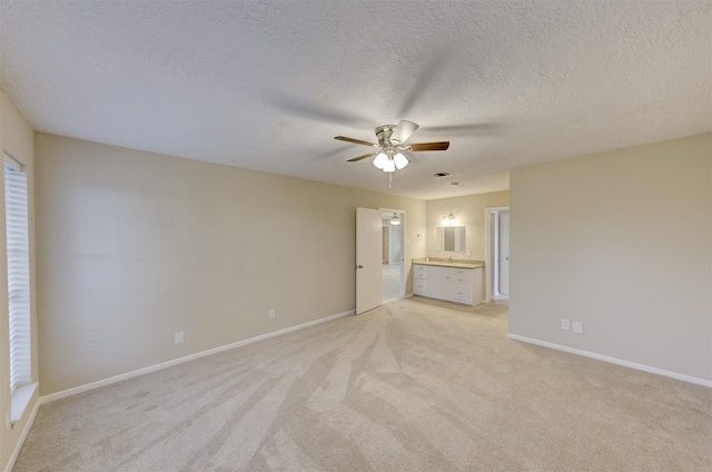 interior space with ensuite bathroom, light colored carpet, a textured ceiling, and ceiling fan