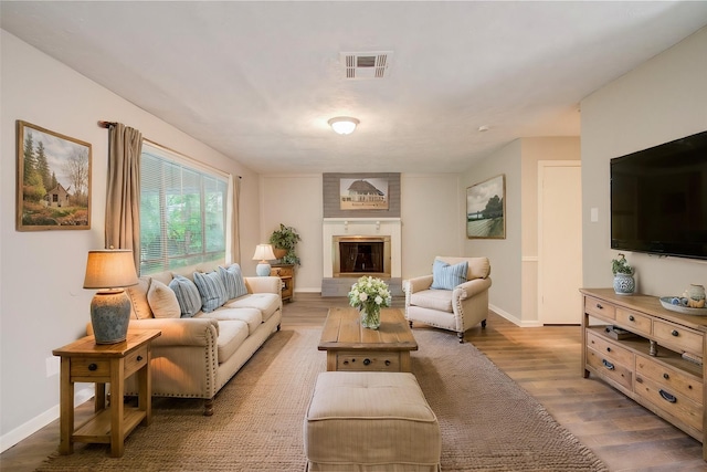 living room with wood-type flooring and a large fireplace