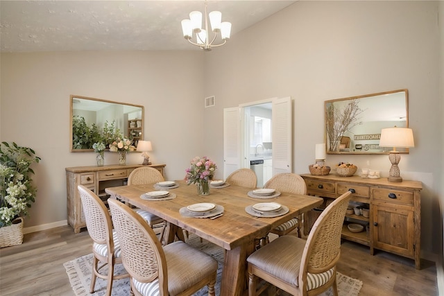 dining space with hardwood / wood-style flooring, vaulted ceiling, sink, and a chandelier