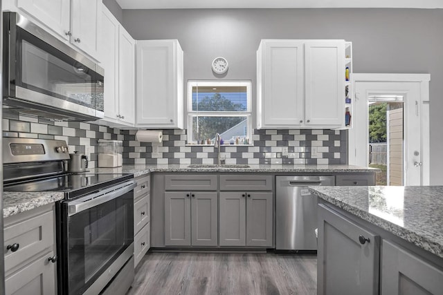 kitchen with tasteful backsplash, appliances with stainless steel finishes, sink, and white cabinets