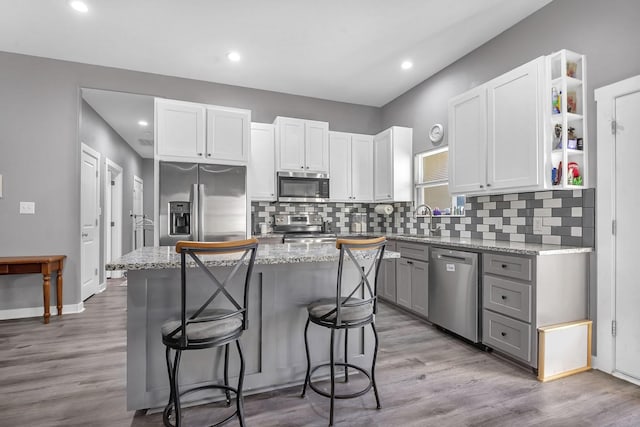 kitchen with a kitchen island, appliances with stainless steel finishes, a breakfast bar, gray cabinetry, and white cabinets