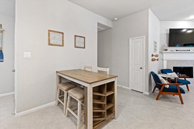 dining space featuring light tile patterned floors and a fireplace