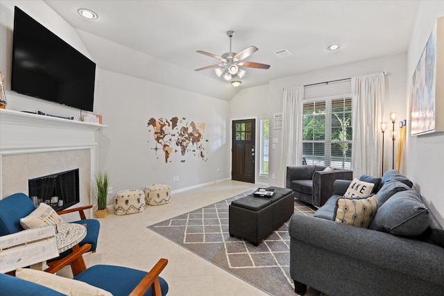 tiled living room with ceiling fan, lofted ceiling, and a tiled fireplace