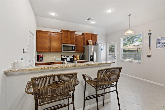 kitchen featuring a breakfast bar area, hanging light fixtures, light tile patterned floors, kitchen peninsula, and stainless steel appliances