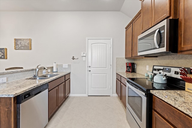 kitchen with sink, appliances with stainless steel finishes, backsplash, light stone countertops, and vaulted ceiling