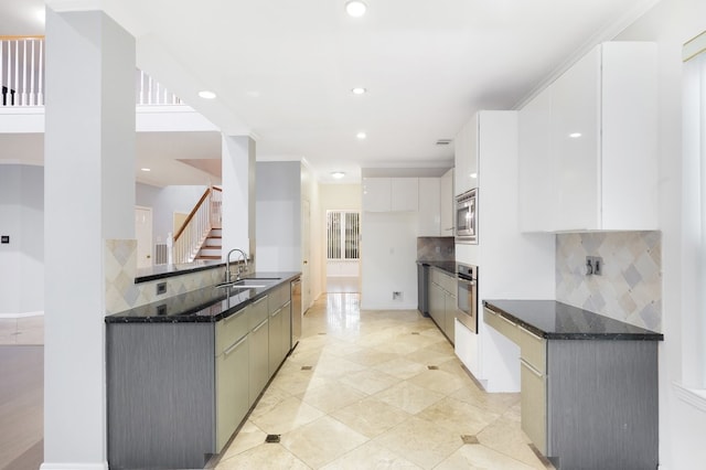 kitchen featuring sink, white cabinetry, dark stone countertops, appliances with stainless steel finishes, and backsplash