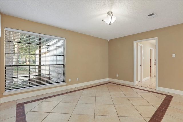 tiled empty room with a textured ceiling