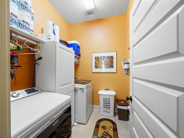 clothes washing area with separate washer and dryer and light tile patterned floors