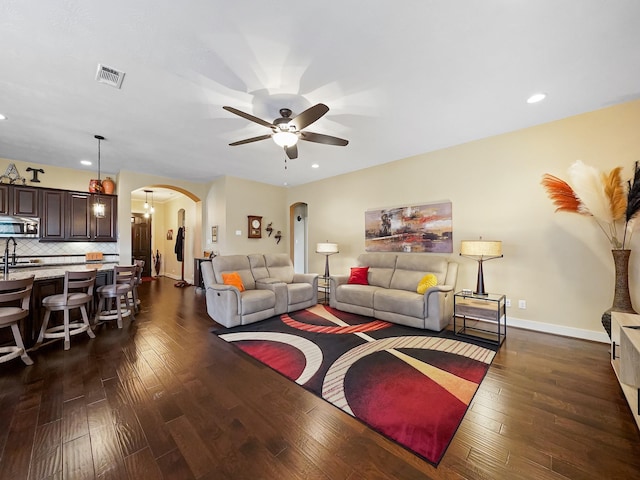 living room with dark wood-type flooring and ceiling fan