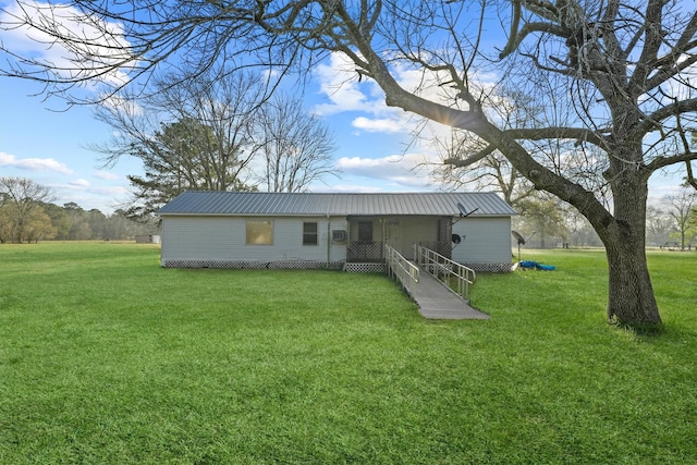 rear view of house featuring metal roof and a yard