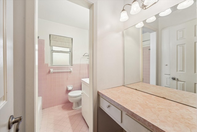 bathroom with walk in shower, tile patterned floors, toilet, tile walls, and vanity