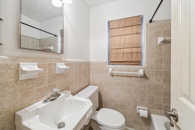 bathroom featuring toilet, sink, and tile walls