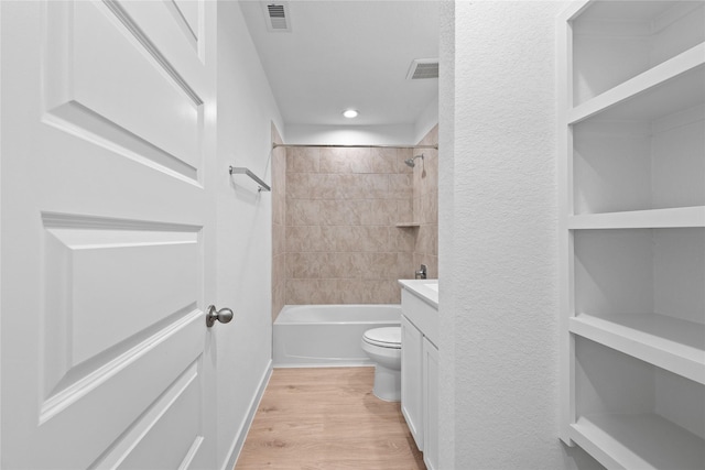 full bathroom with vanity, hardwood / wood-style floors, tiled shower / bath combo, and toilet