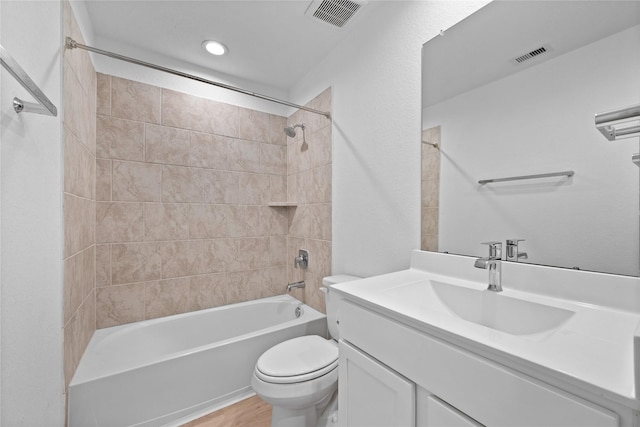 full bathroom featuring hardwood / wood-style flooring, vanity, toilet, and tiled shower / bath