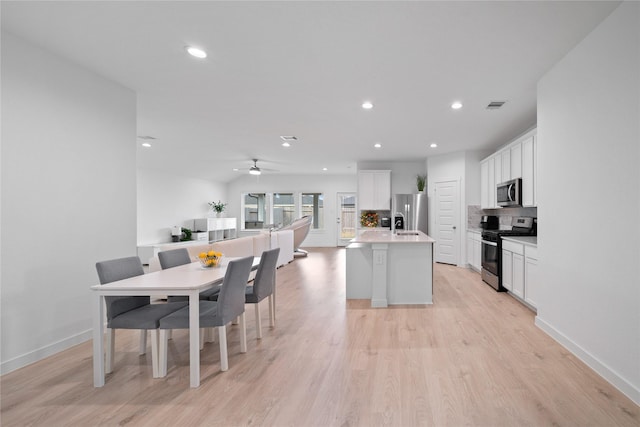 kitchen with stainless steel appliances, white cabinetry, and a center island with sink