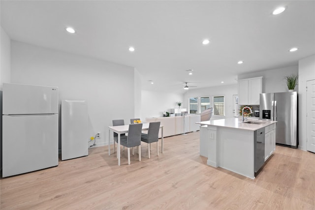 kitchen with an island with sink, sink, white cabinets, light hardwood / wood-style floors, and stainless steel appliances