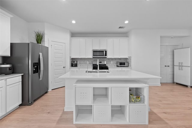 kitchen with sink, white cabinetry, a center island with sink, light hardwood / wood-style flooring, and appliances with stainless steel finishes