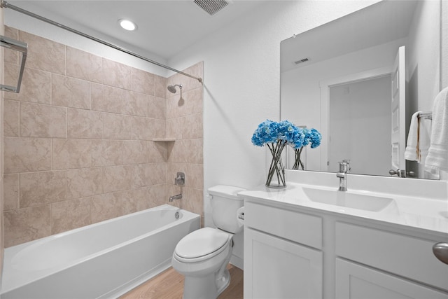 full bathroom featuring vanity, hardwood / wood-style floors, tiled shower / bath combo, and toilet