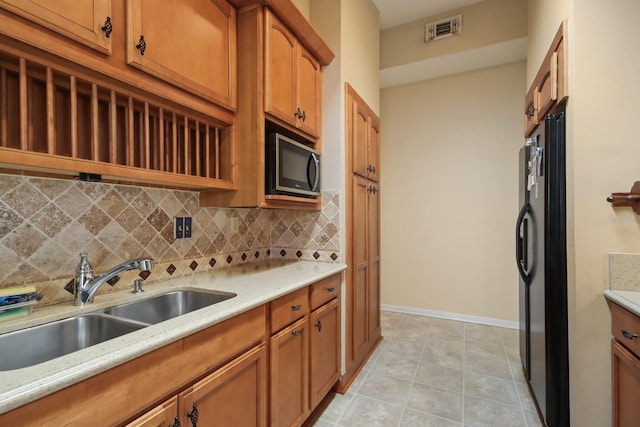 kitchen with tasteful backsplash, sink, light tile patterned floors, and black fridge with ice dispenser