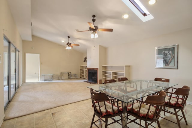 dining space featuring ceiling fan, light colored carpet, and lofted ceiling with skylight