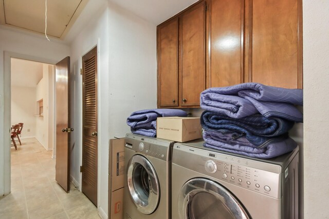 laundry area featuring cabinets, light tile patterned floors, and washer and clothes dryer