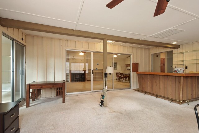 basement featuring carpet floors, wooden walls, and ceiling fan