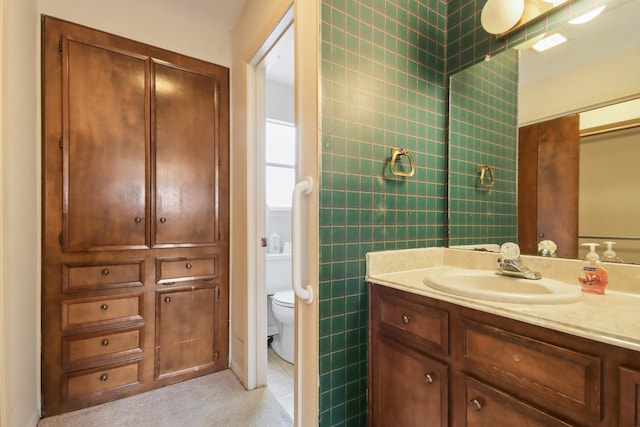 bathroom featuring vanity, tile walls, and toilet