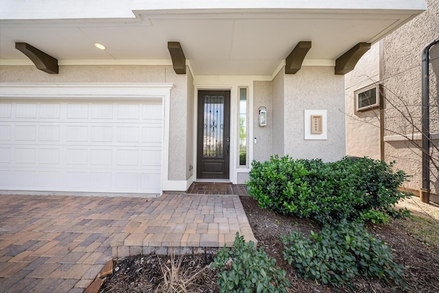 view of exterior entry with a garage and a wall mounted AC