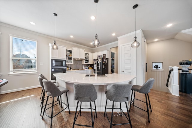 kitchen featuring a breakfast bar area, white cabinetry, hanging light fixtures, a large island, and black appliances