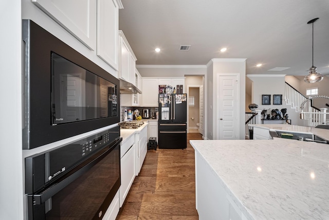 kitchen featuring decorative light fixtures, white cabinetry, light stone counters, black appliances, and crown molding