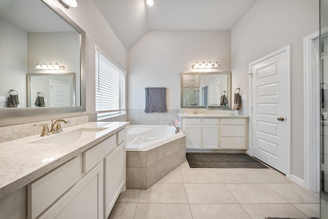 bathroom with tile patterned floors, tiled bath, vaulted ceiling, and vanity