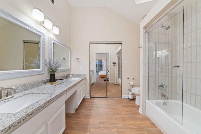 full bathroom featuring vanity, toilet, tiled shower / bath combo, and vaulted ceiling