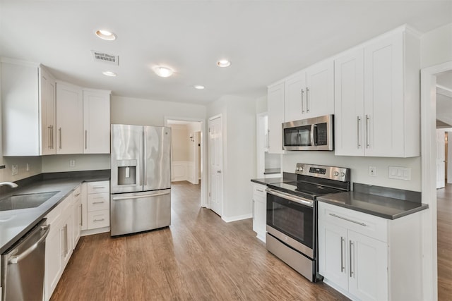 kitchen featuring light wood-type flooring, appliances with stainless steel finishes, sink, and white cabinets