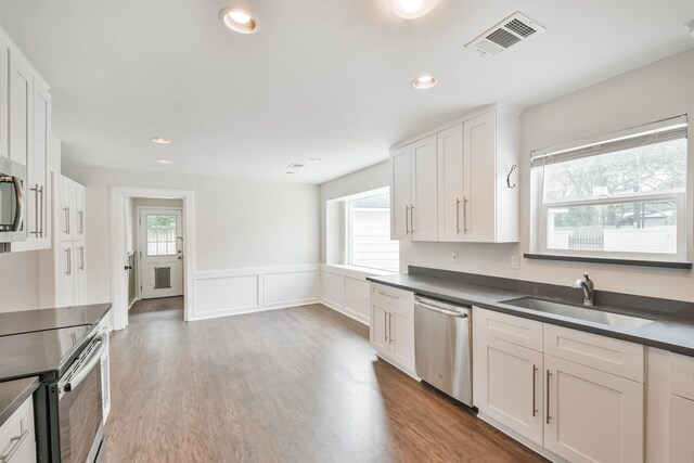 kitchen featuring white cabinetry, sink, stainless steel appliances, and hardwood / wood-style floors