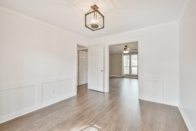 spare room featuring crown molding, hardwood / wood-style flooring, and an inviting chandelier