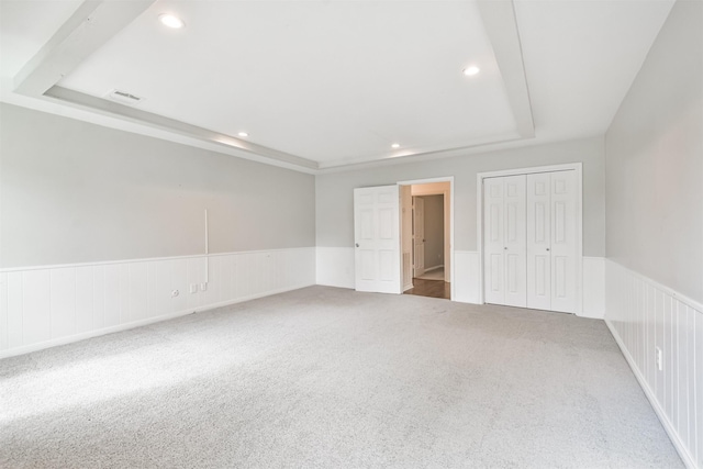 unfurnished bedroom with a raised ceiling, carpet floors, and a closet