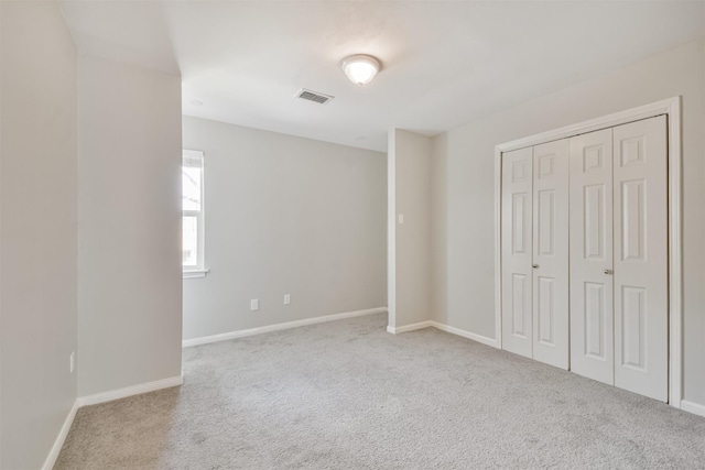 unfurnished bedroom with light colored carpet and a closet