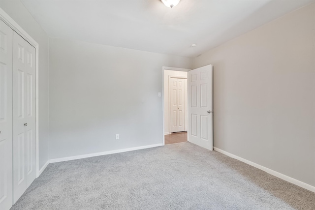 unfurnished bedroom featuring light carpet and a closet